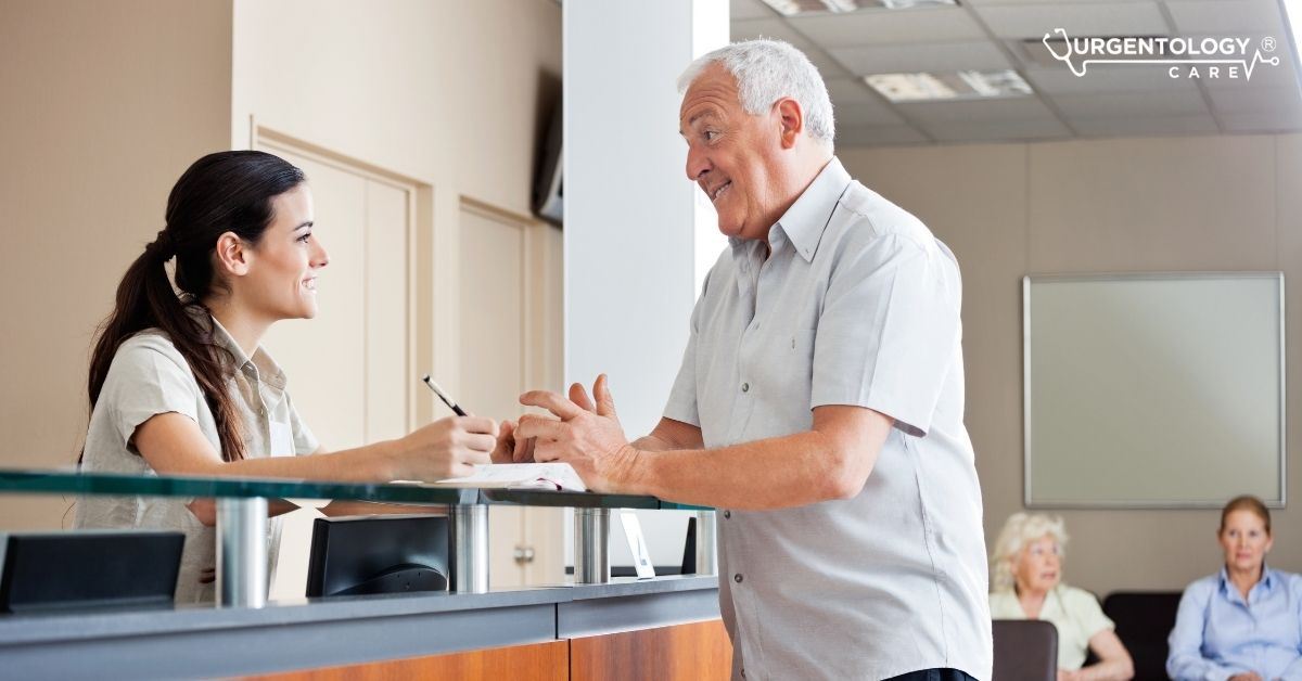 man at emergency room counter talking to female nurse.